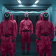 A group of Squid Game guards in pink jumpsuits enter a room in a screenshot from the series.